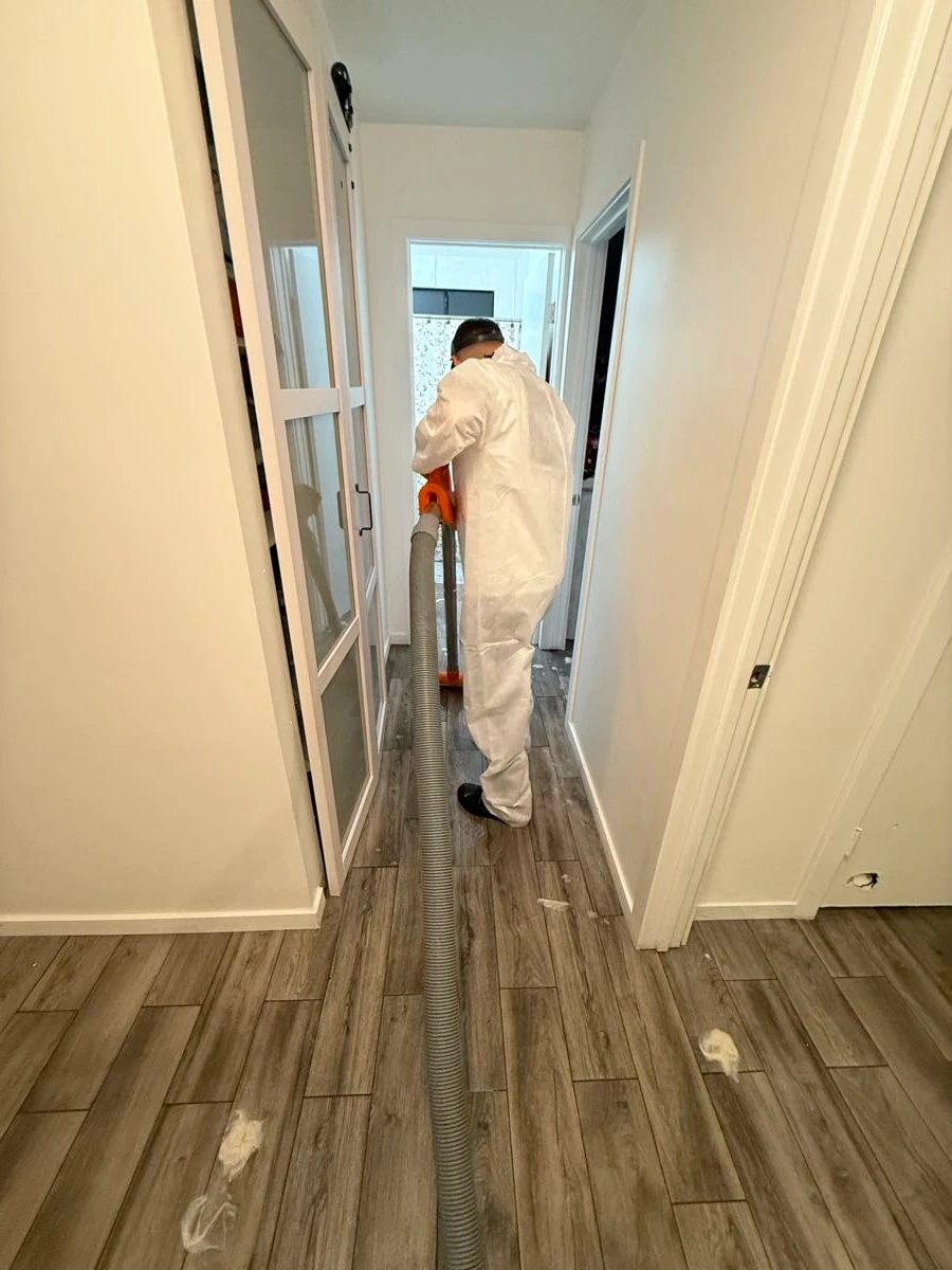 Technician running a HEPA vacuum hose down a hallway during mold cleaning