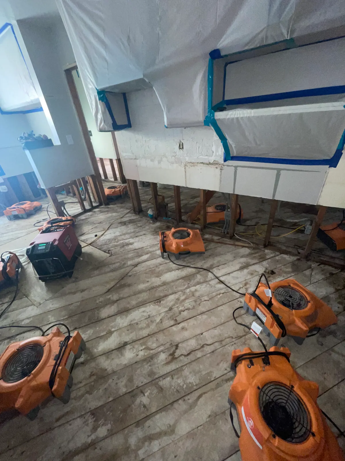 Air movers and drying equipment beside exposed wall framing
